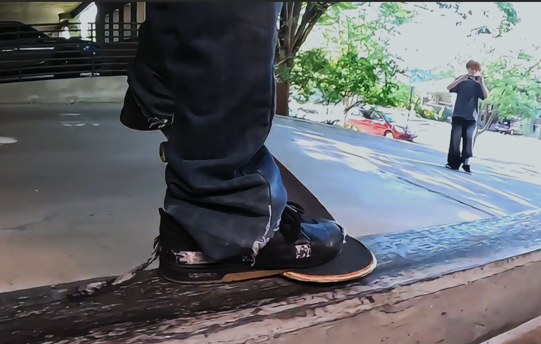 Editorial image of worn skate shoes and a skateboard beside a concrete ledge